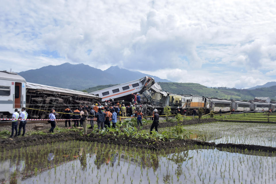 Rescuers inspect the wreckage after the collision between two trains in Cicalengka, West Java, Indonesia, Friday, Jan. 5, 2024. The trains collided on Indonesia's main island of Java on Friday, causing several carriages to buckle and overturn and killing at least a few people, officials said. (AP Photo/Abdan Syakura)