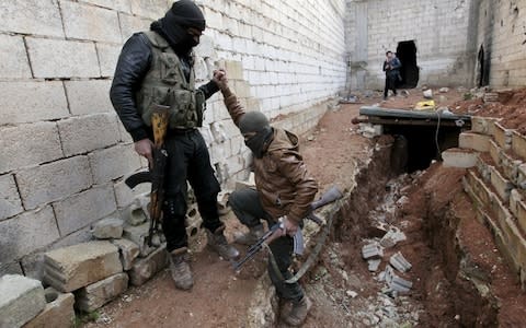  A Turkish-backed Syrian rebel helps his fellow rebel in the town of Tadef in Aleppo Governorate - Credit: REUTERS