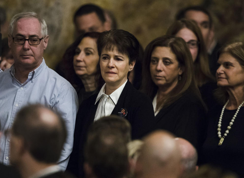 Andrea Wedner, center, who was wounded at the Pittsburgh synagogue attack that killed 11 people last year, stands with others as they are acknowledged by Pennsylvania lawmakers who came together in an unusual joint session to commemorate the victims of synagogue attack, Wednesday, April 10, 2019, at the state Capitol in Harrisburg, Pa. (AP Photo/Matt Rourke)