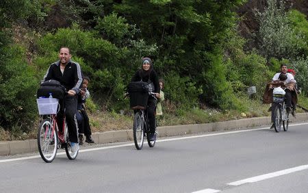 Migrants from Syria ride their bicycles near the Greek border in Macedonia June 17, 2015. REUTERS/Ognen Teofilovski