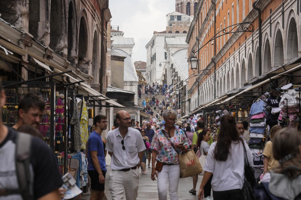 Tourists walk in a crowded street in Venice, Italy, Wednesday, Sept. 13, 2023. The Italian city of Venice has been struggling to manage an onslaught of tourists in the budget travel era. The stakes for the fragile lagoon city are high this week as a UNESCO committee decides whether to insert Venice on its list of endangered sites. (AP Photo/Luca Bruno)