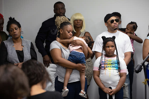 Rayshard Brooks's widow Tomika Miller holds one of her daughters as family lawyers speaks to media.