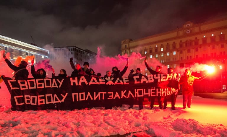 Russian opposition supporters burn flares and hold a banner -- which translates as "Free Nadezhda, free political prisoners" -- during an unsactioned rally in Moscow, as they demand the release of Ukrainian pilot Nadiya Savchenko