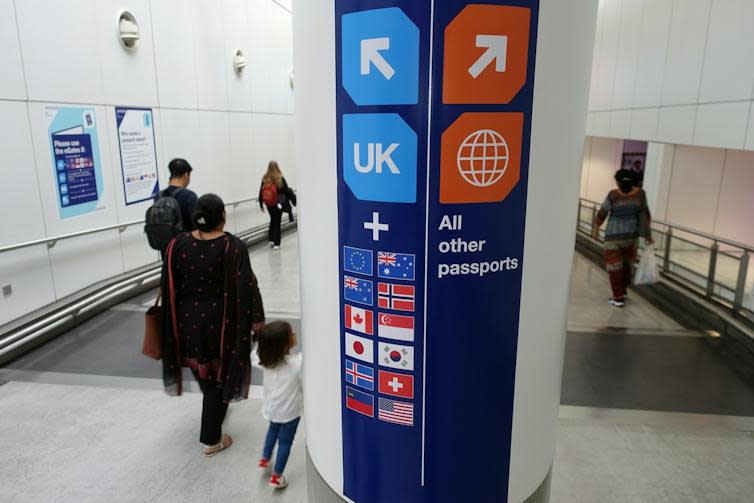 Families walk past a passport control sign in an airport that points people with UK, EU and some other European passports in a different direction to all other passports.