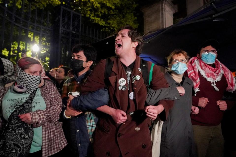 Protesters link arms as other police officers enter the campus of Columbia University on Tuesday night. REUTERS