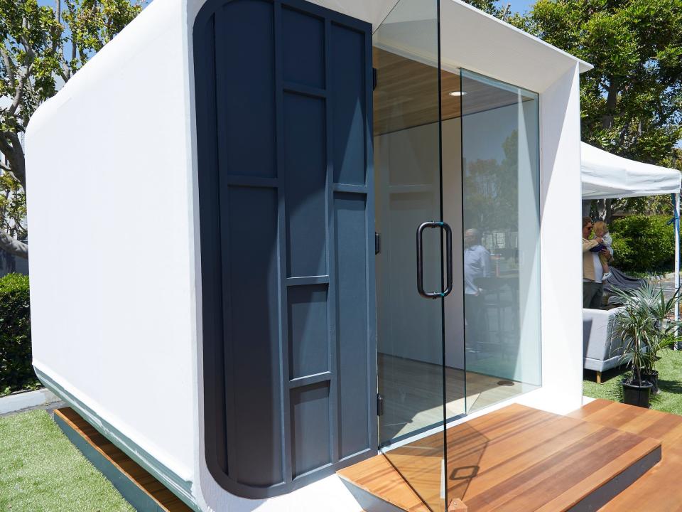 A tiny home on a patch of grass with glass trimmings.