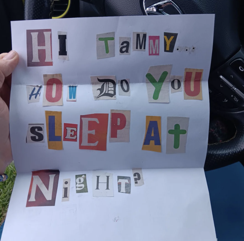 Paper with cutout letters forming the message "HI TaMMy HOW DO YOU SLEeP AT NIGHT?" held in a car