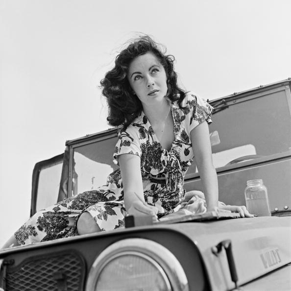 <p>Elizabeth enjoyed painting, especially at a young age. Here, the actress is seen painting outside in the summer of 1947 on the hood of a car.</p>