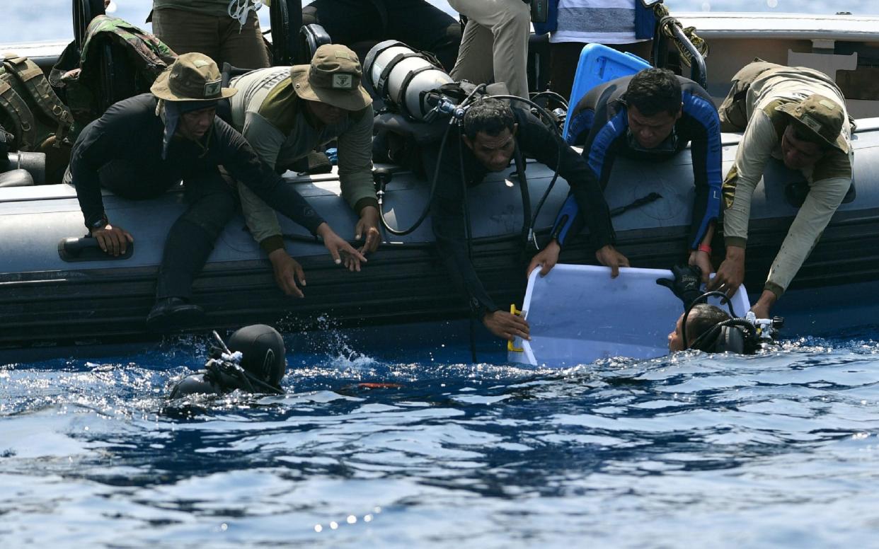 An Indonesian Navy diver holds a recovered 