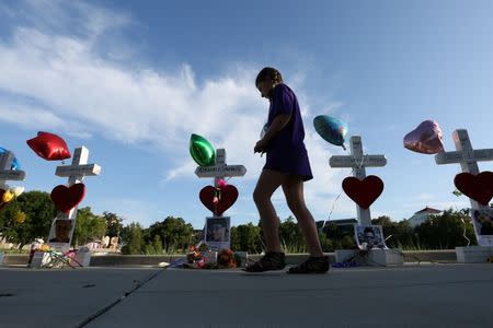 A child walks past a row of 49 wood crosses commemorating the victims of the Pulse night club shooting in Orlando, Florida, U.S., June 17, 2016. REUTERS/Carlo Allegri