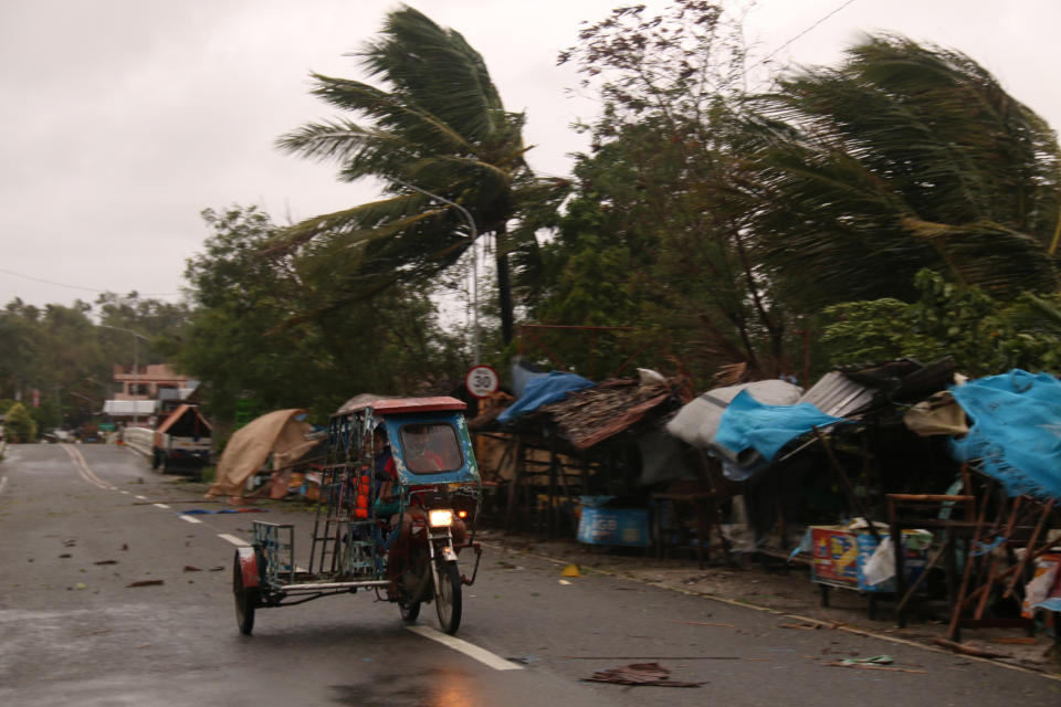 A man drives his tricycle along a road as strong winds caused by typhoon Vongfong hit Catbalogan city, Western Samar province, eastern Philippines, Thursday May, 14, 2020. A strong typhoon slammed into the eastern Philippines on Thursday after authorities evacuated tens of thousands of people while trying to avoid the virus risks of overcrowding emergency shelters. (AP Photo/Simvale Sayat)