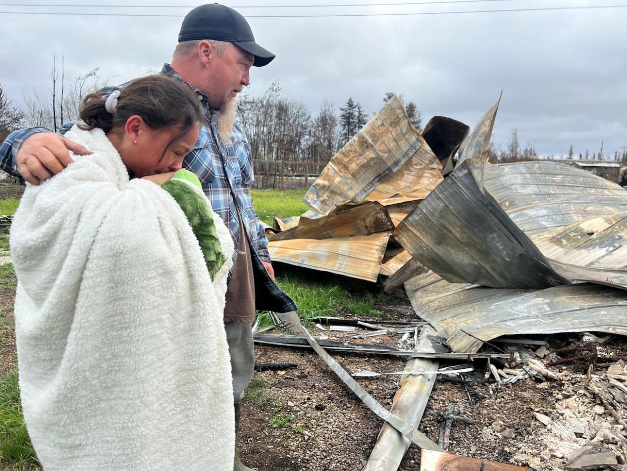 Paul Flamand stands with his daughter, Dakota Steinwand, to survey the damage to his home in Enterprise, N.W.T., from last month's wildfire. Residents have been returning to Enterprise in recent days, since the evacuation order for the community was lifted.  (Marc Winkler/CBC - image credit)