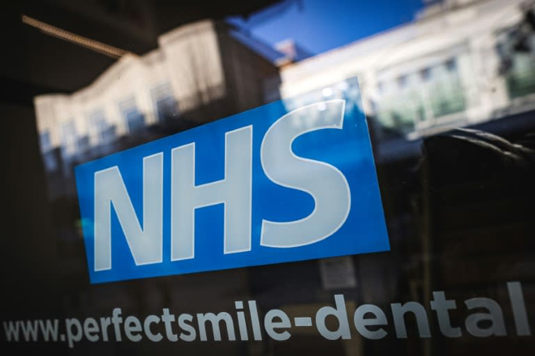 Le logo du NHS, Service de santé publique britannique, sur la vitrine d'un cabinet dentaire à Bracknell, le 10 janvier 2024 (Adrian DENNIS)