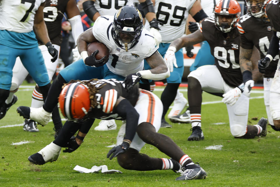 Jacksonville Jaguars running back Travis Etienne Jr. (1) jumps over Cleveland Browns safety Ronnie Hickman during the second half of an NFL football game, Sunday, Dec. 10, 2023, in Cleveland. (AP Photo/Ron Schwane)