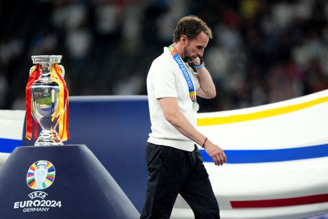 A dejected Gareth Southgate walks past the European Championship trophy