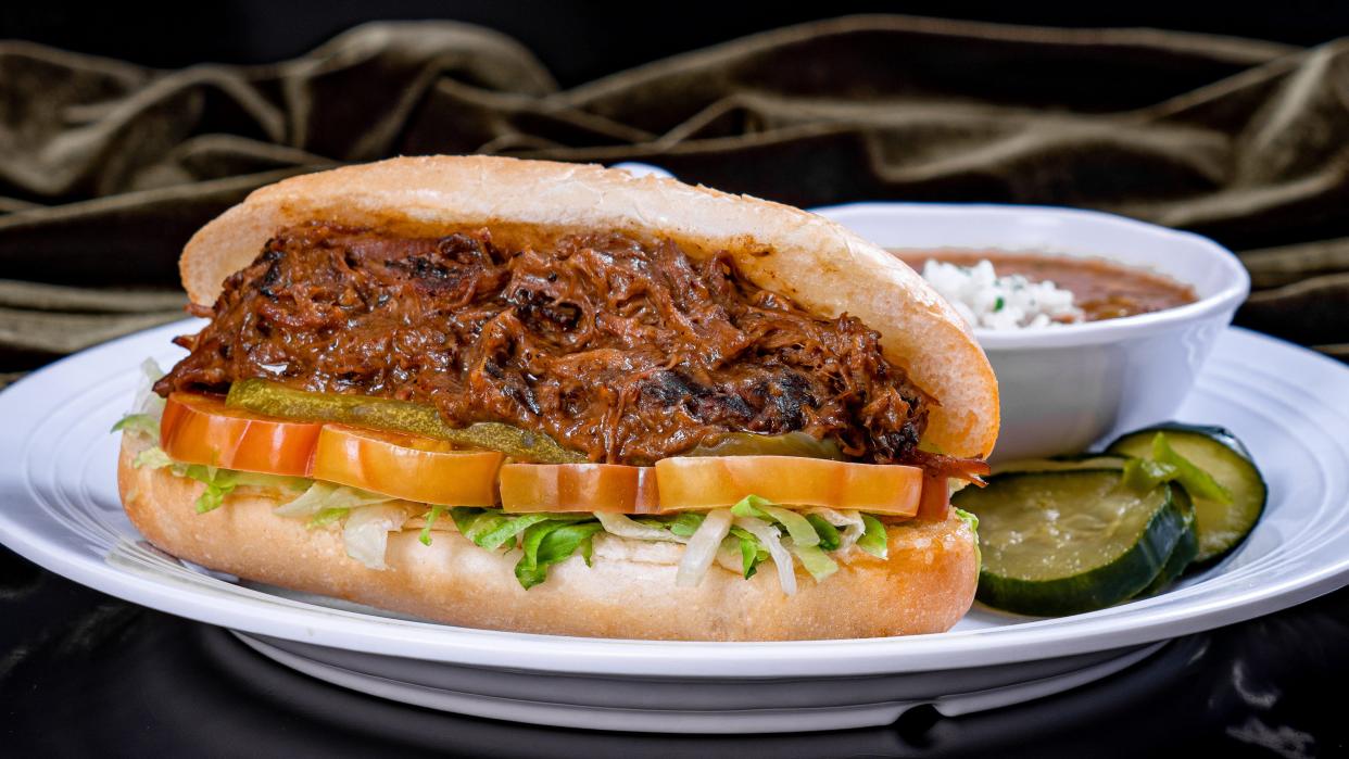 Beef Po'boy Sandwich – slow-cooked beef in gravy dressed with shredded lettuce, tomato, pickle and mayonnaise on a toasted New Orleans French bread, served with red beans & rice and house-made pickles.