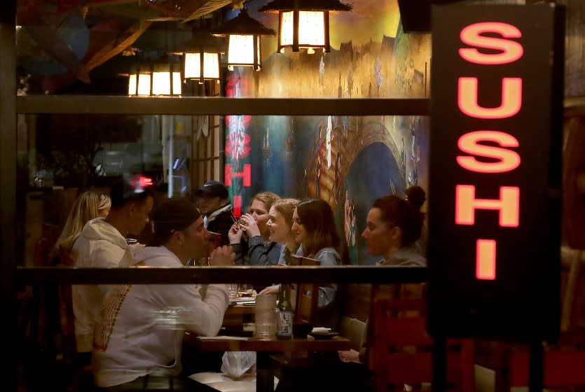 LONG BEACH, CALIF. - MAR. 15, 2021. Customers dine inside a sushi restaurant in Long Beach on Monday night, Mar. 15, 2021. Under L.A. County reopening guidelines, restaurants can open indoors at 25% capacity but must maintain eight feet of distance between tables. Indoor malls can operate at 50% capacity. (Luis Sinco/Los Angeles Times)