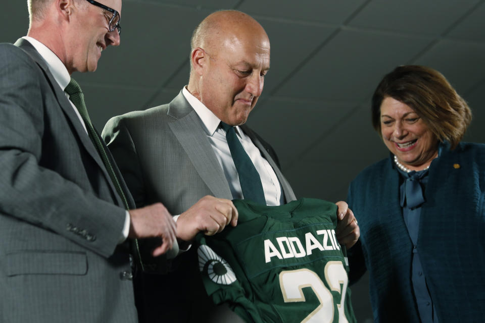 Steve Addazio, center, looks down at a jersey presented to him by athletic director Joe Parker, left, and President Joyce McConnell during an announcement that Addazio has been hired as the new head football coach at Colorado State University at a news conference at the school Thursday, Dec. 12, 2019, in Fort Collins, Colo. (AP Photo/David Zalubowski)
