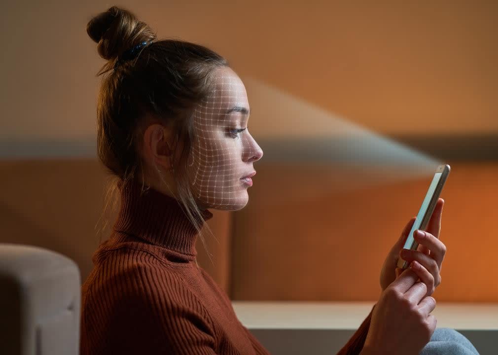 A woman scans face using facial recognition system on smartphone.