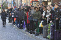 Commuters and tourists wait for a bus at Gare du Nord train station in Paris, Wednesday, Dec. 18, 2019. With French President Emmanuel Macron under heavy pressure over his pension reform plans, government officials are meeting with employers and unions on Wednesday to consider the way forward. (AP Photo/Michel Euler)