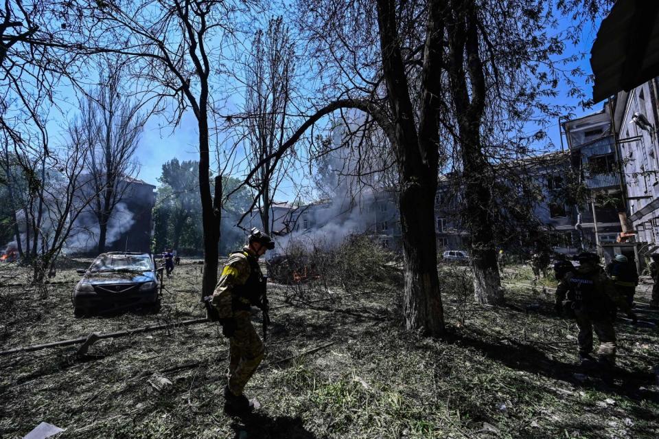 Ukrainian servicemen walk in rubble