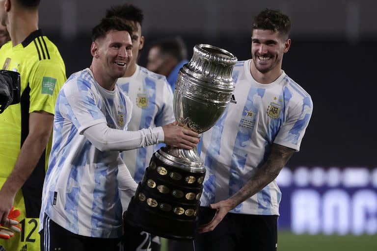 Argentina's Lionel Messi (L) and Argentina's Rodrigo De Paul (R) hold the Copa America trophy while posing for a picture after the end of their South American qualification football match for the FIFA World Cup Qatar 2022 against Bolivia at the Monumental Stadium in Buenos Aires on September 9, 2021. (Photo by Juan Ignacio RONCORONI / POOL / AFP)