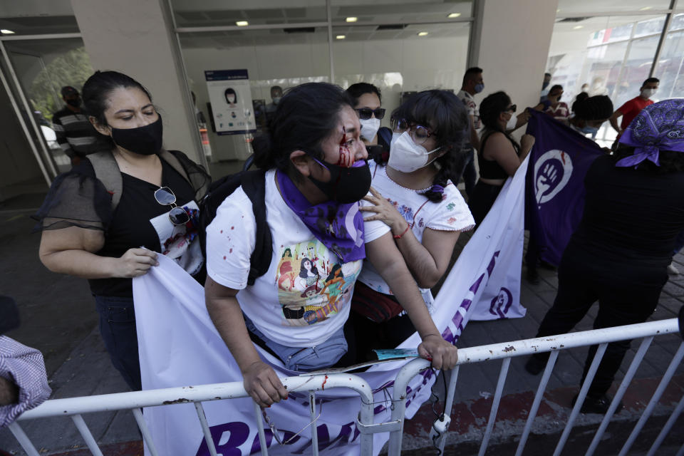 FILE - In this Feb. 24, 2021 file photo, a woman who has been injured during a scuffle with supporters of local ruling party politician Felix Salgado is helped by a fellow demonstrator during a visit by Mexican President Andres Manuel Lopez Obrador and Argentina's President Alberto Fernandez in Iguala, Mexico. Citing multiple accusations of rape and sexual assault against Salgado, the women were protesting against Salgado's candidature and the ruling Morena party for backing him. (AP Photo/Eduardo Verdugo, File)