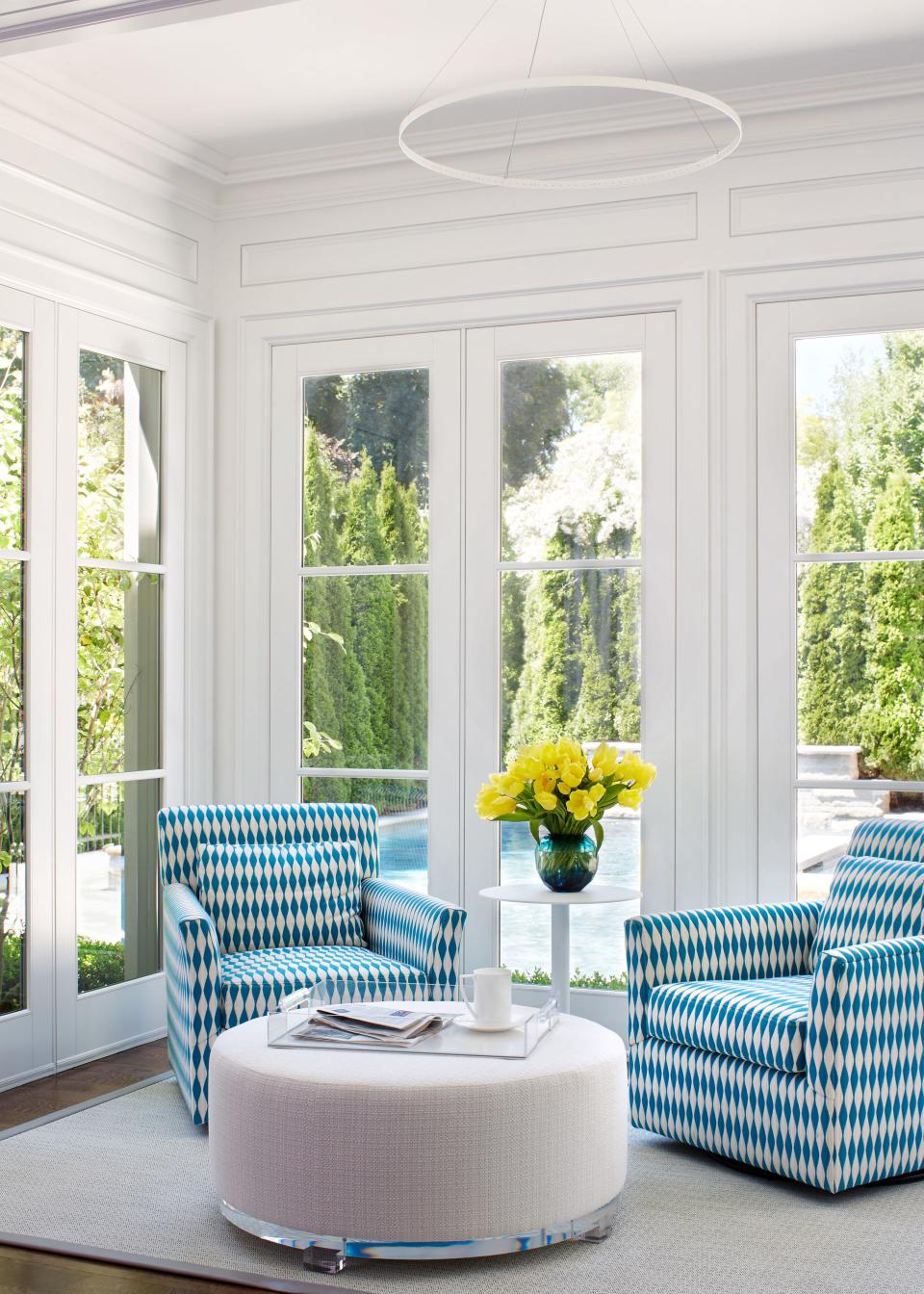 In the sunroom, turquoise-and-white swivel chairs from Jonathan Adler draw from the tranquil hues of the outdoor swimming pool. Underfoot, a rubberized Bolon rug makes mopping up water a breeze.