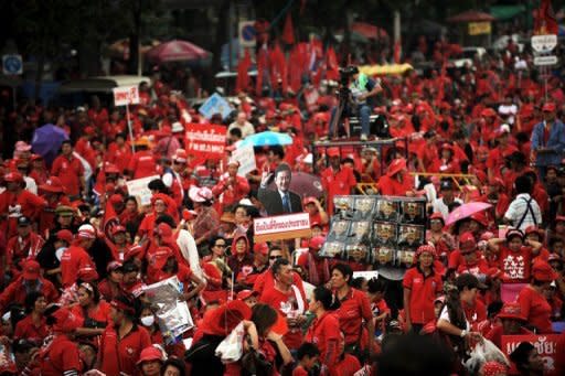 An anti-government 'Red Shirt' protester carries a cut-out of exiled ex-premier Thaksin Shinawatra (C) during a rally at Democracy Monument in downtown Bangkok. Thousands of anti-government 'Red Shirt' demonstrators took to Bangkok's streets Saturday amid a heavy police presence, marking a year since the start of protests in the capital that turned deadly