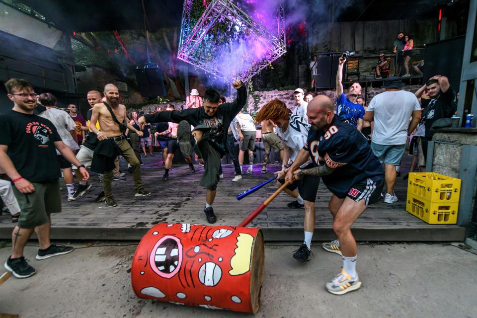 Revellers destroy a barrel symbolising Russia during a performance at a rave party in central Kyiv, Ukraine August 27, 2022.