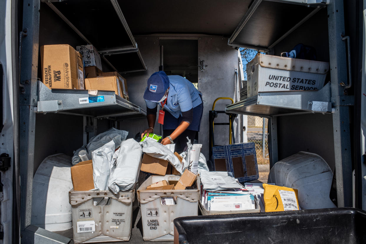A U.S. Postal Service employee organizes packages in the pack of a mail truck in Houston. 