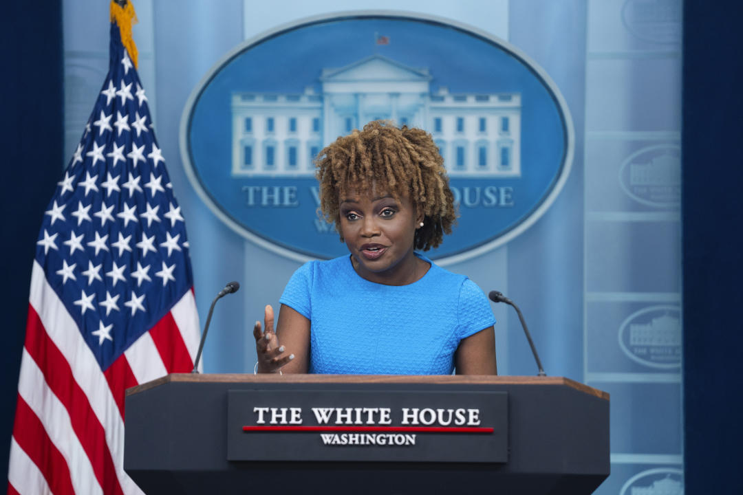 White House press secretary Karine Jean Pierre, in a sky blue dress, speaks at the podium during a briefing at the White House.