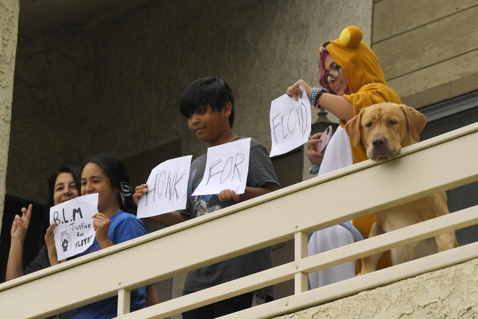 People and a dog watch from a balcony as demonstrators pass by during a protest, Saturday, June 6, 2020, in Simi Valley, Calif. over the death of George Floyd. Floyd died in police custody on Memorial Day in Minneapolis. (AP Photo/Mark J. Terrill)