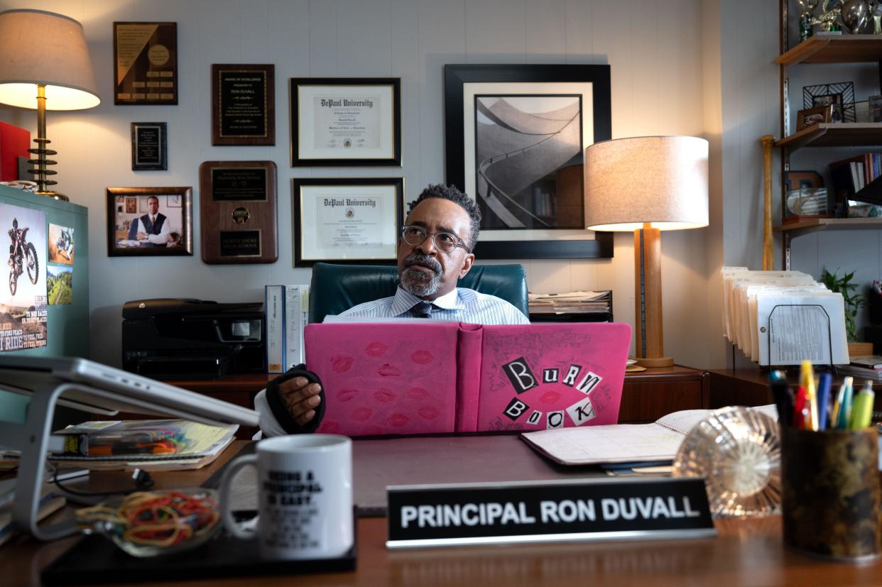  Tim Meadows as Principal Duvall sits behind his desk with the pink-covered Burn Book in Mean Girls. 