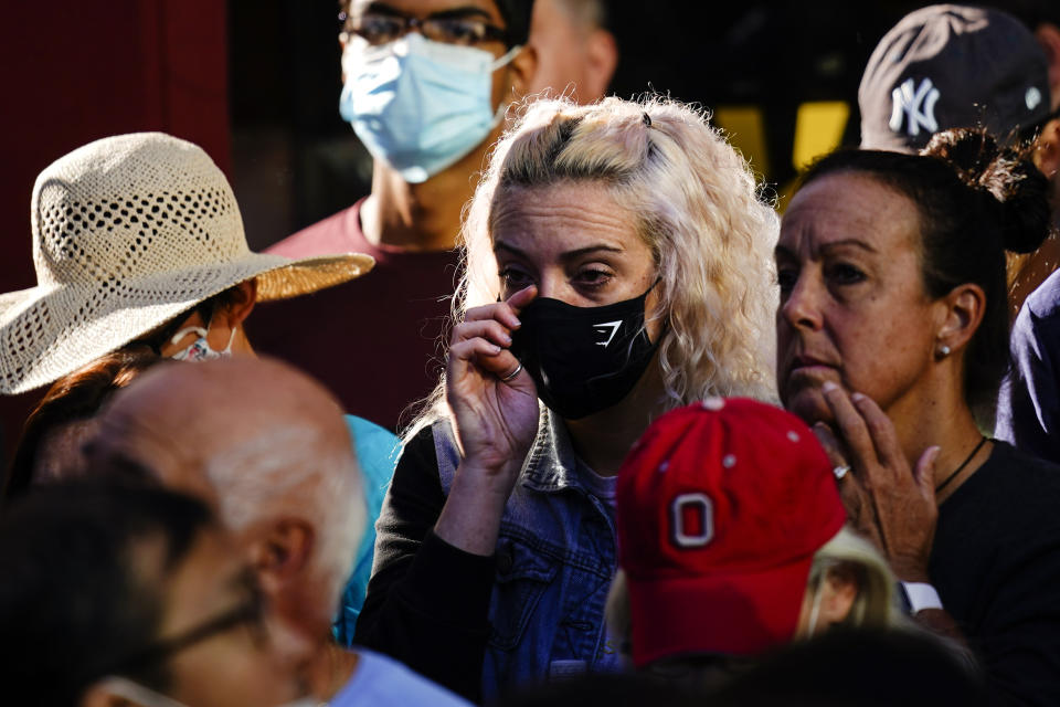 A person wipes her eye as she gathers with others outside the National September 11 Memorial and Museum during a ceremony marking the 20th anniversary of the 9/11 terrorist attacks, Saturday, Sept. 11, 2021, in New York. (AP Photo/Matt Rourke)