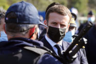 French President Emmanuel Macron speaks with a police officer during a visit on the strengthening border controls at the crossing between Spain and France, at Le Perthus, France, Thursday, Nov. 5, 2020. (Guillaume Horcajuelo, Pool via AP)