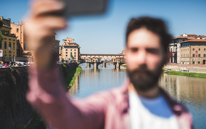 A selfie-taker in front of the original museum of selfies, the Vasari corridor, which runs above the Ponte Vecchio - This content is subject to copyright.