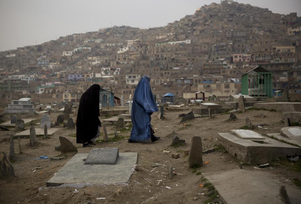 In this Friday, March 7, 2014 photo, Afghan women cross a cemetery in the center of Kabul, Afghanistan. A gender and development specialist and human rights activist, Afghan Wazhma Frogh says her experience characterizes the women’s rights movement in her country- after 12 years, billions of dollars and countless words emanating from the West commiserating with Afghan women, the successes are fragile, the changes superficial and vulnerable. (AP Photo/Anja Niedringhaus)