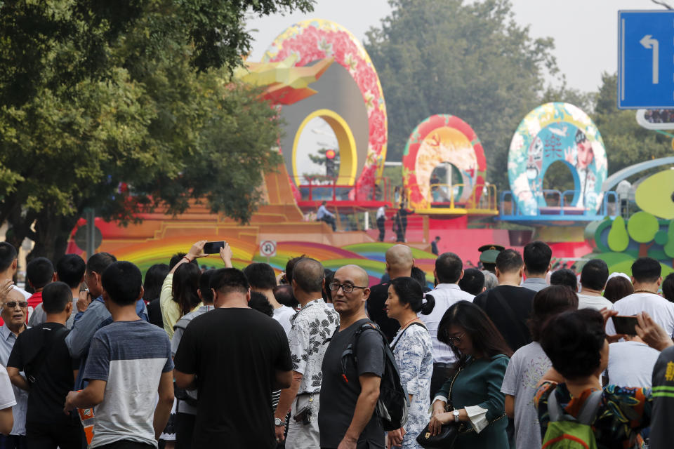 Residents watch a float behind barricade line as Chinese military vehicles and floats in preparation for the parade for the 70th anniversary of the founding of the People's Republic of China, in Beijing, Tuesday, Oct. 1, 2019. Tuesday's event marks the anniversary of the Oct. 1, 1949, announcement of the founding of the People's Republic of China by then-leader Mao Zedong following a civil war. (AP Photo/Andy Wong)