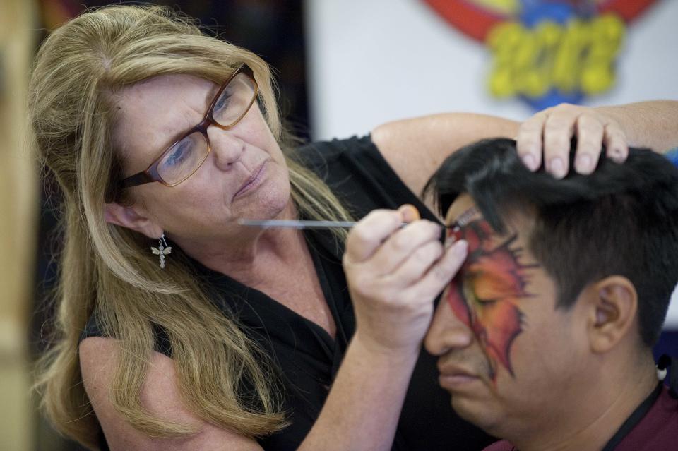 In a July 31, 2012 photo, Donna Hofstee, aka "Dizzy Darla" the clown, demonstrates face painting techniques on Jose Morales, or "Cascarita," at the third annual Clown Campin' in Ontario, Calif. The week-long event is held for clowns across the United States and Canada to learn, get inspired, and network. (AP Photo/Grant Hindsley)