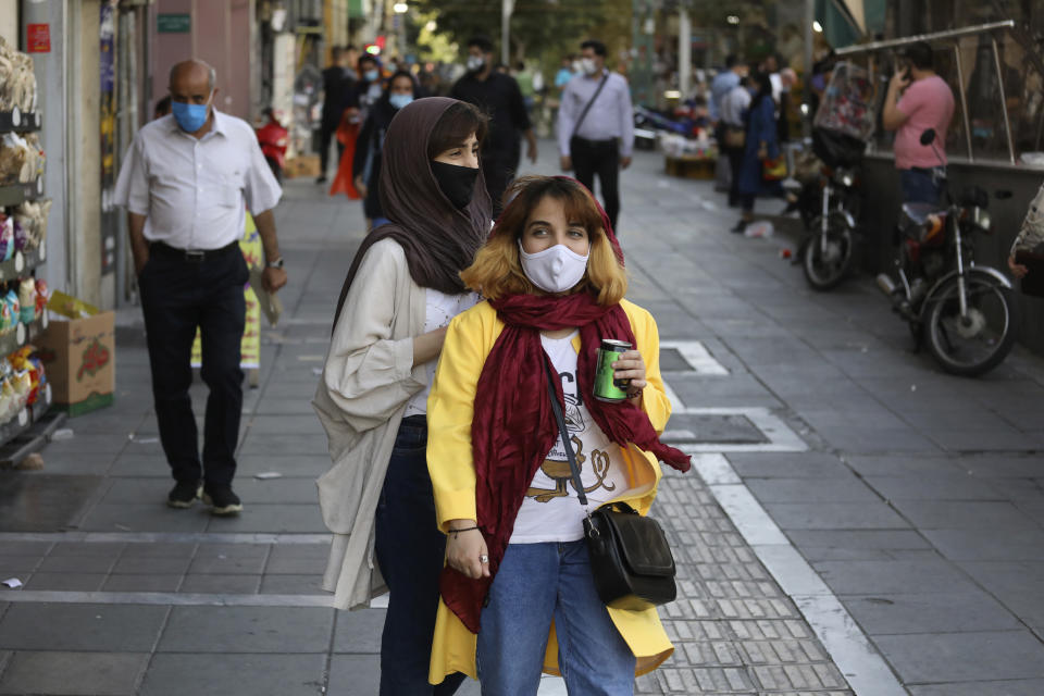 People wearing protective face masks to help prevent the spread of the coronavirus walk on a sidewalk of a commercial street in Tehran, Iran, Sunday, Sept. 20, 2020. Iran's president dismissed U.S. efforts to restore all U.N. sanctions on the country as mounting economic pressure from Washington pushed the local currency down to its lowest level ever on Sunday. (AP Photo/Vahid Salemi)