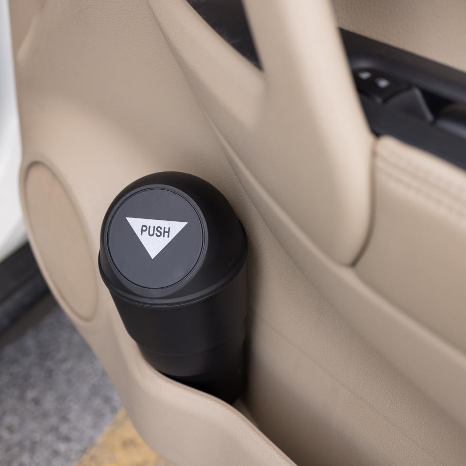 The mini trash can, with a round push lid, in a car's side door cup holder