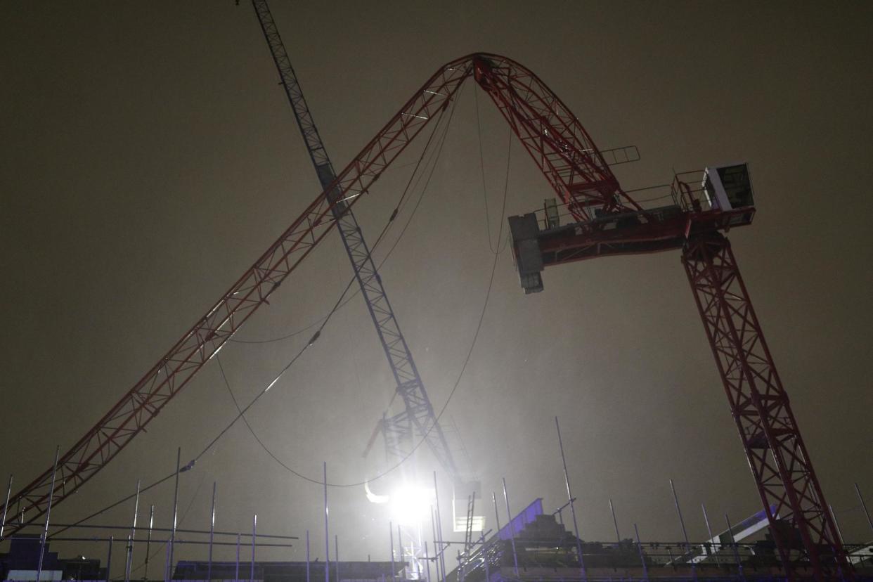 A crane partially collapsed on a building site in south-west London amid high winds across the capital on Tuesday: PA