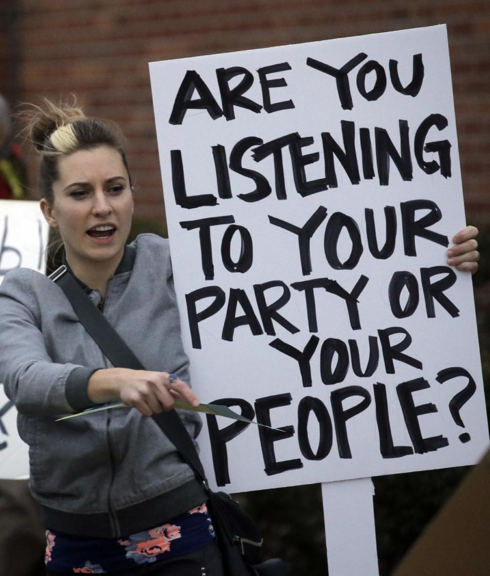 Holly Cobb Robinson holds her sign outside the Brighton High School before U.S. Rep. Jason Chaffetz town hall meeting Thursday, Feb. 9, 2017, in Cottonwood Heights, Utah. His visit came as the congressman spends time in his home state, visiting with Muslim leaders and holding a town hall Thursday night in which he's expected to be greeted by a small band of protesters and face some sharp questions from constituents who are frustrated about his refusal to investigate President Donald Trump's ties to Russia. (AP Photo/Rick Bowmer)