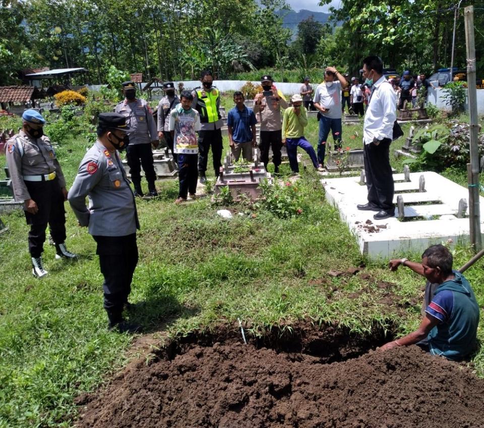 Robyek (sitting down) with a crowd watching him after he had dug up his wife's grave. ― Picture via Facebook/PonorogoUp