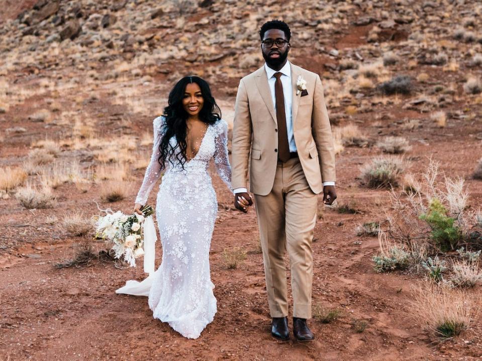 A bride and groom pose for a photo in the desert.