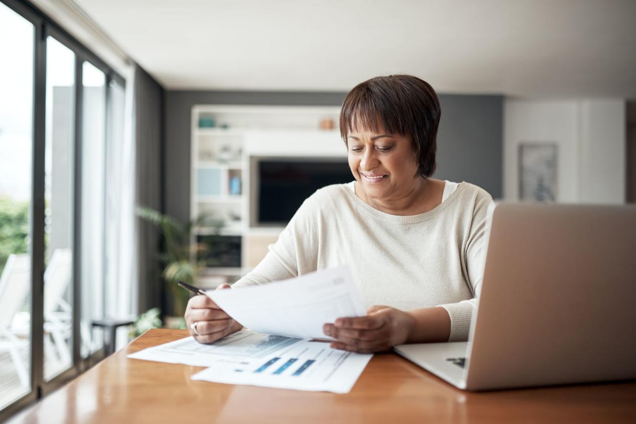 Cropped shot of a happy senior woman sitting alone in her living room and going through paperwork