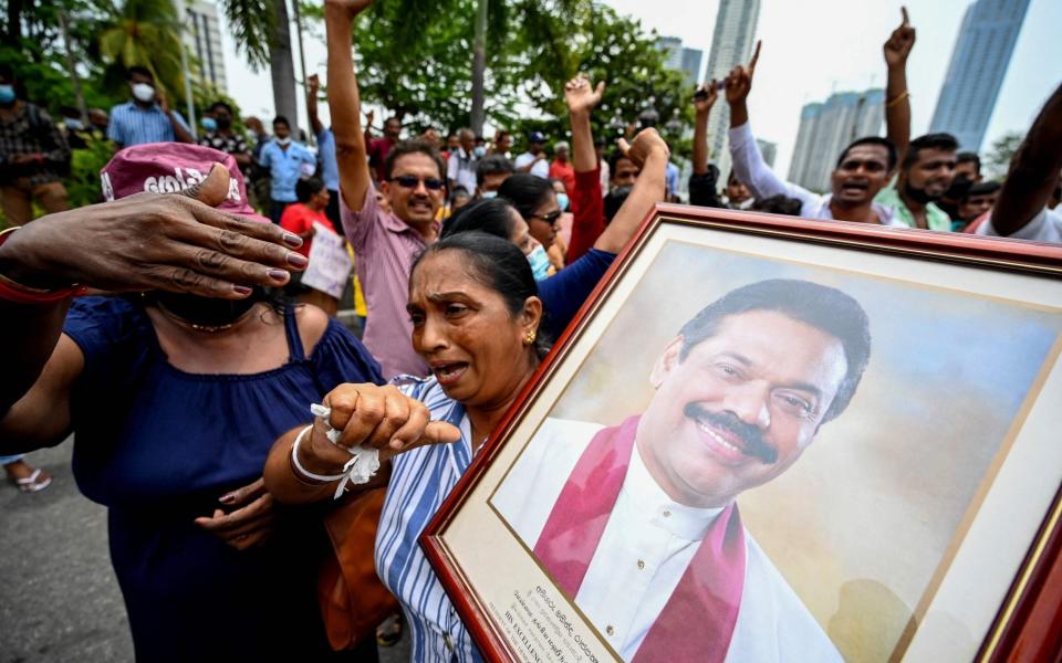 Pro-government supporters hold Prime Minister Mahinda Rajapaksa's portrait while protesting outside the prime ministers residence in Colombo on May 9, 2022 - Ishara S. Kodikara /AFP 