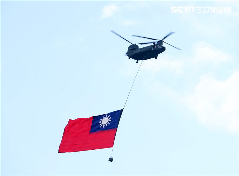 雙十國慶國軍展開空中全兵力預演，一架CH-47SD直升機吊掛巨幅國旗橫越總統府。（圖/記者邱榮吉攝影）