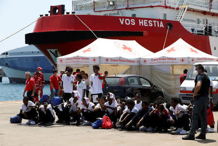 FILE PHOTO: Migrants sit on the ground after disembarking from Vos Hestia ship of NGO "Save the Children" in the Sicilian harbour of Augusta, Italy August 4, 2017. REUTERS/Antonio Parrinello/File Photo